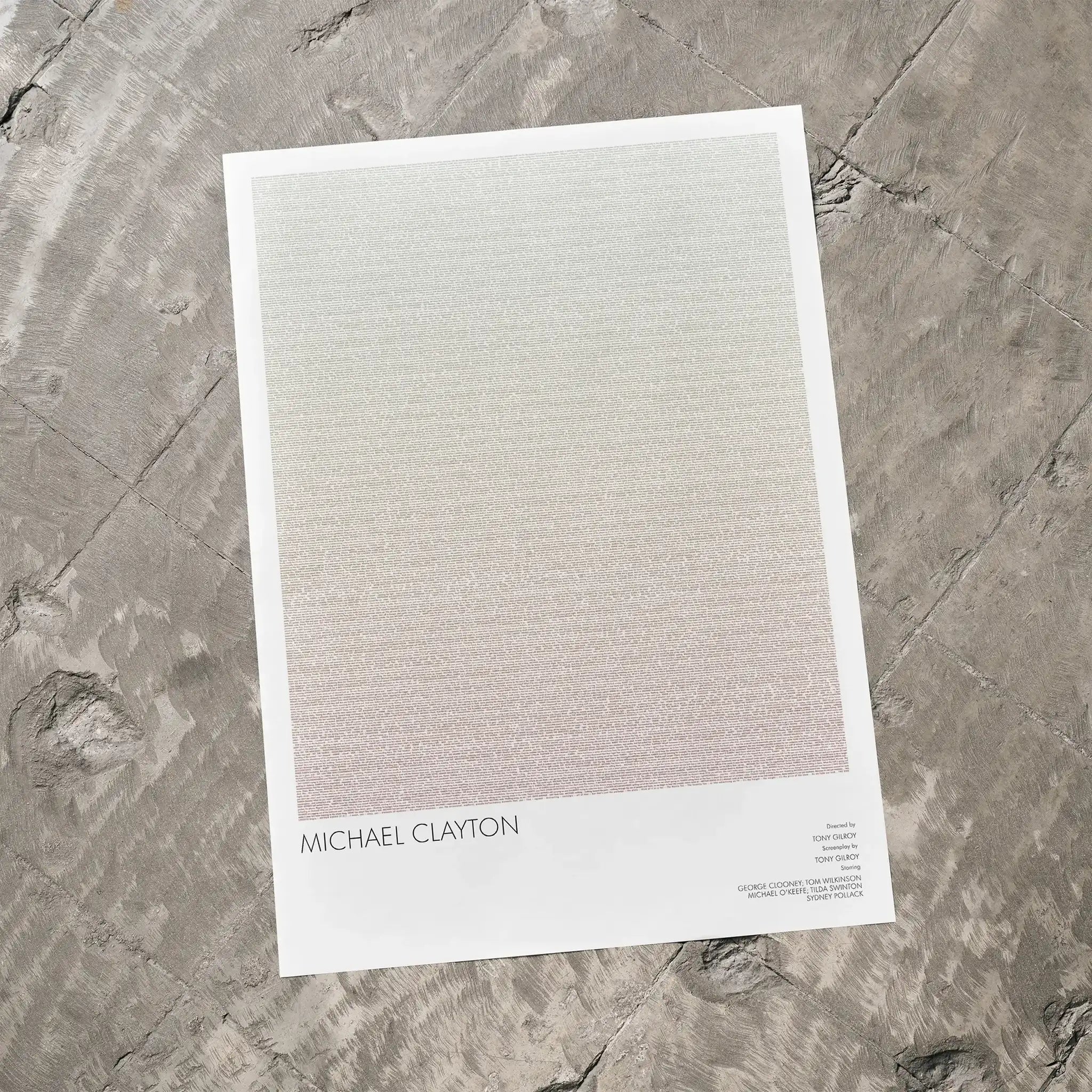 A Michael Clayton movie script poster laid flat on a textured floor surface.