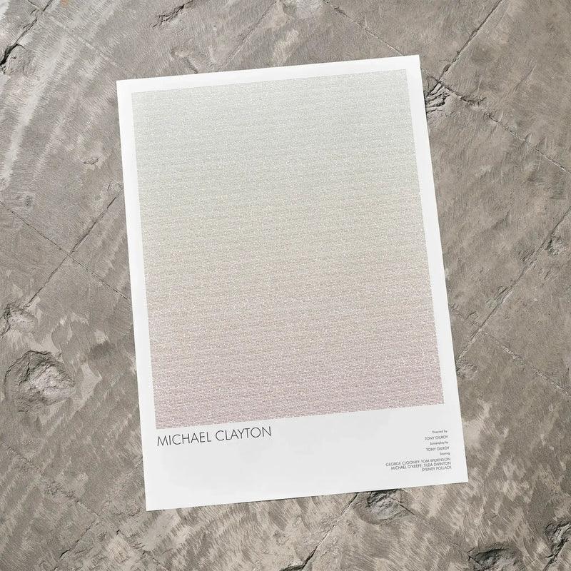 A Michael Clayton movie script poster laid flat on a textured floor surface.