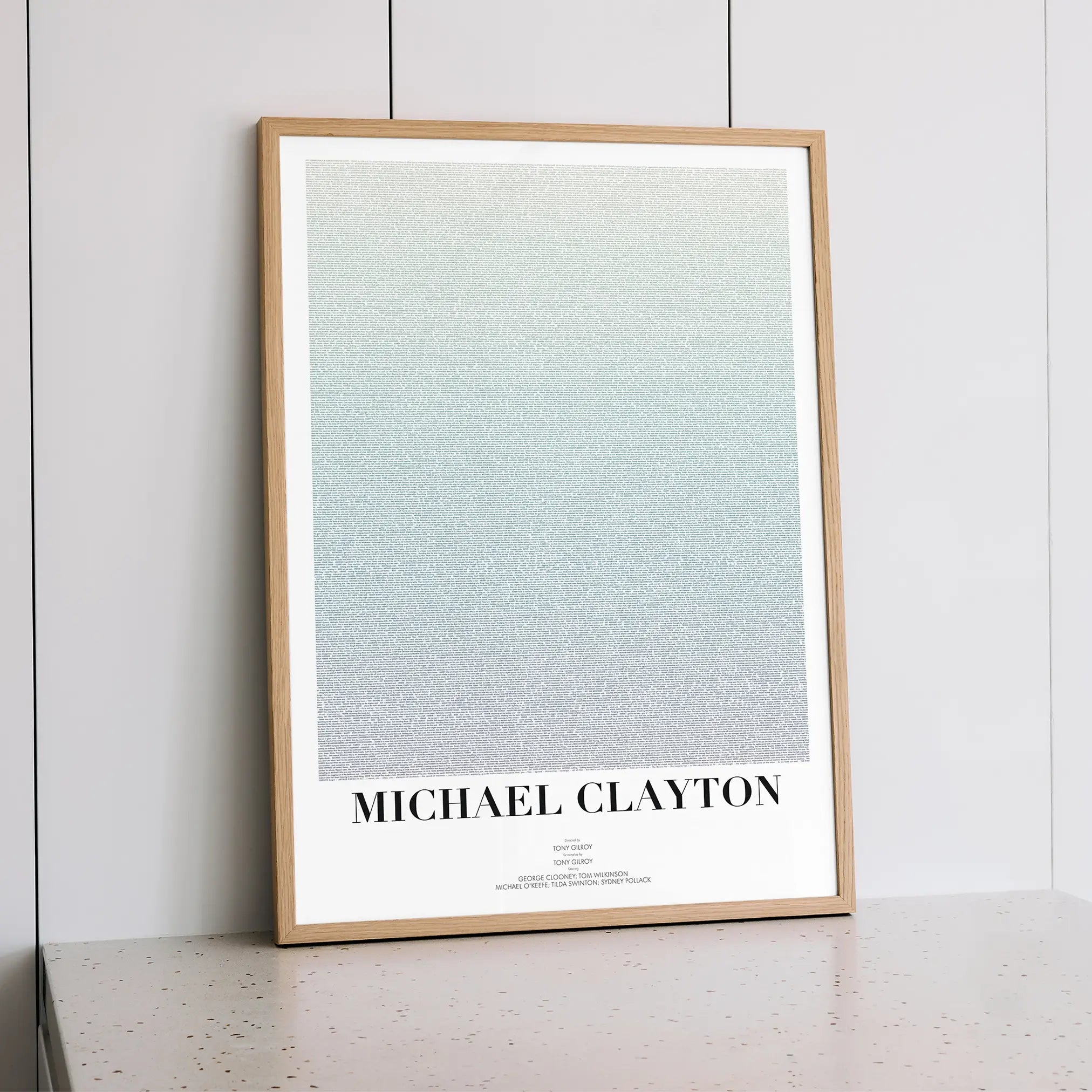 A framed Michael Clayton movie script poster styled within a calm interior space.