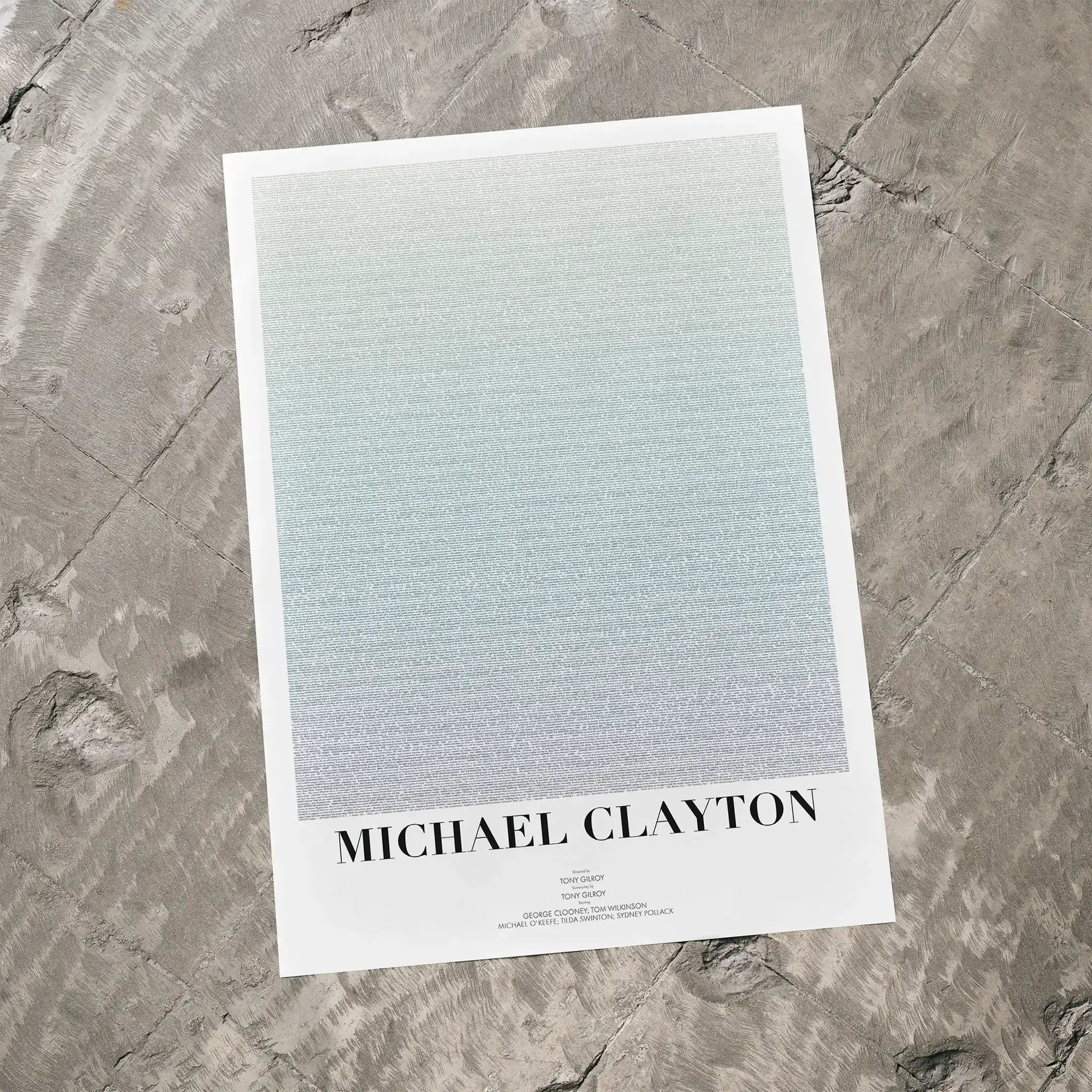 A Michael Clayton movie script poster laid flat on a textured floor surface.