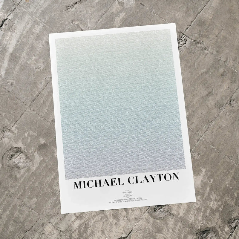A Michael Clayton movie script poster laid flat on a textured floor surface.