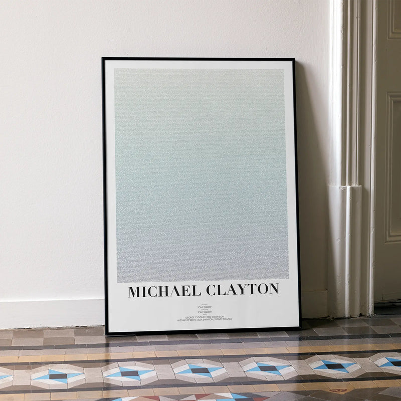 A framed Michael Clayton movie script poster leaning against a wall in a minimalist interior.