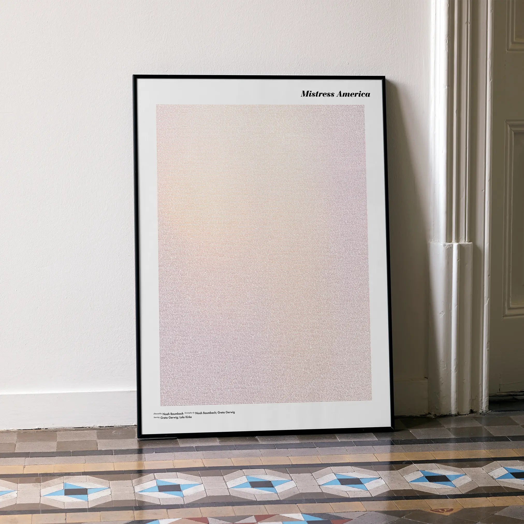 A framed Mistress America movie script poster leaning against a wall in a minimalist interior.