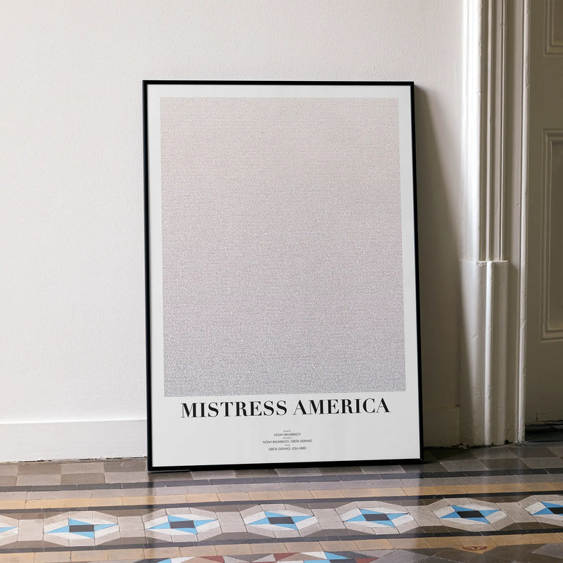 A framed Mistress America movie script poster leaning against a wall in a minimalist interior.