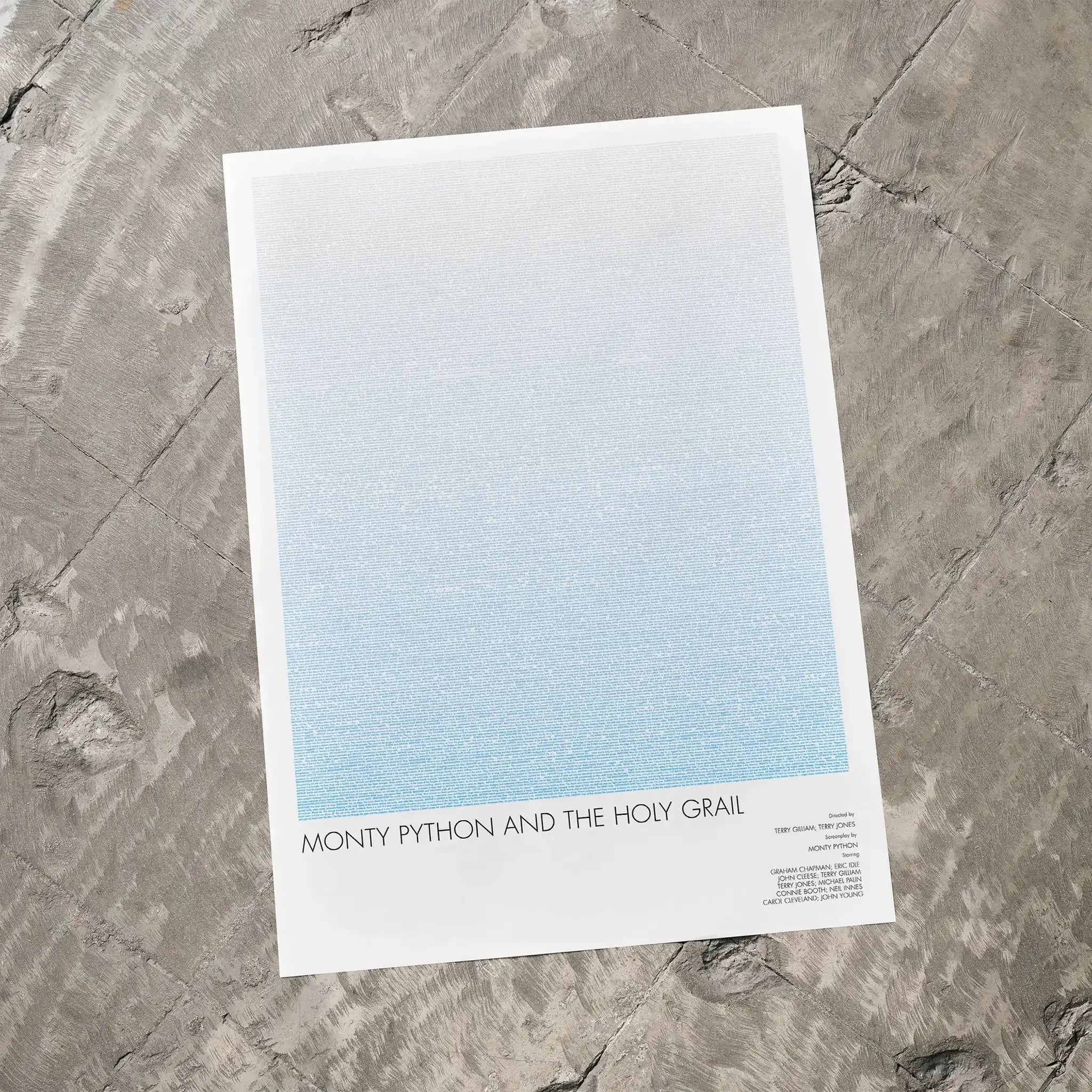 A Monty Python and the Holy Grail movie script poster laid flat on a textured floor surface.