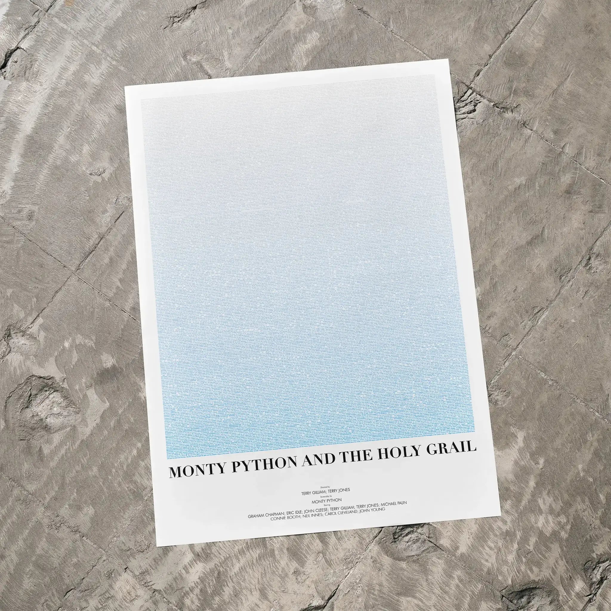A Monty Python and the Holy Grail movie script poster laid flat on a textured floor surface.