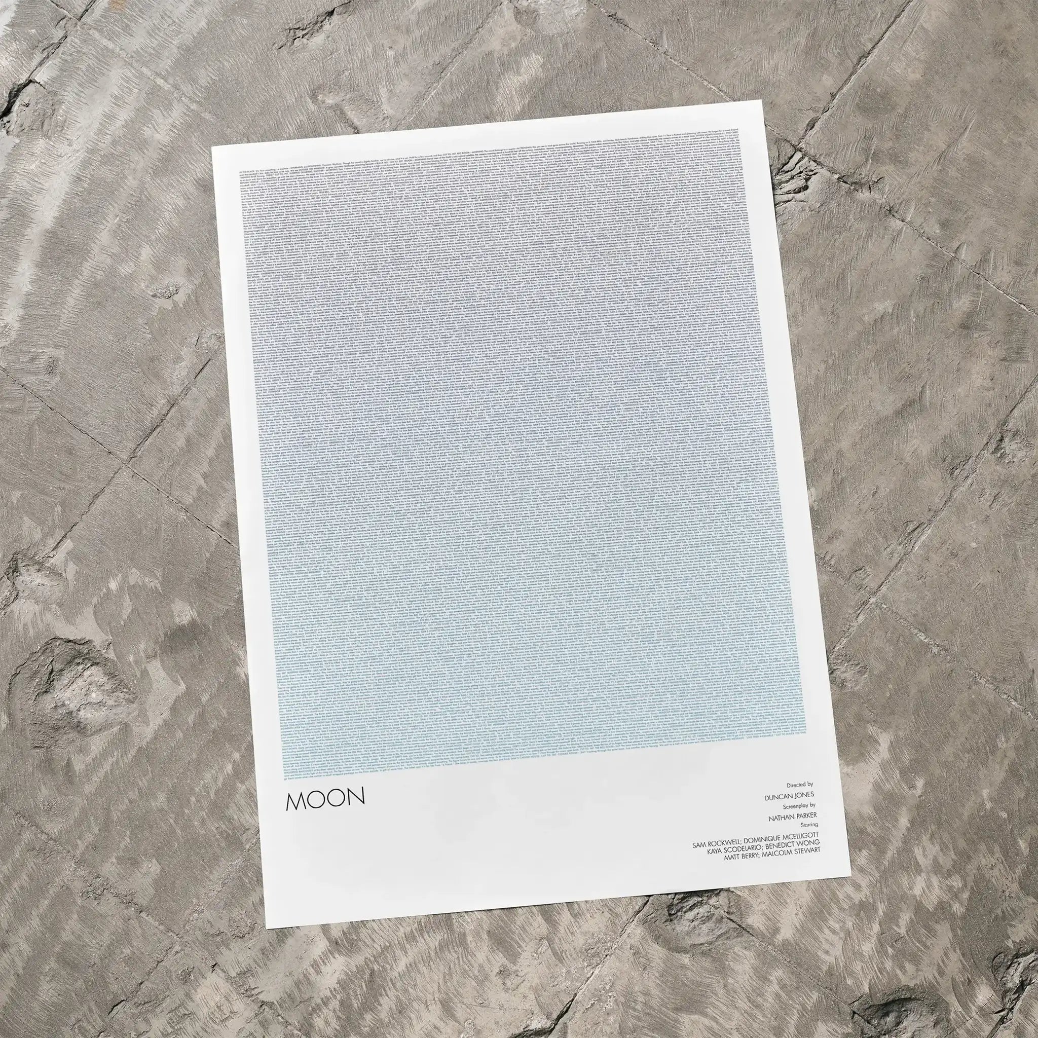 A Moon movie script poster laid flat on a textured floor surface.