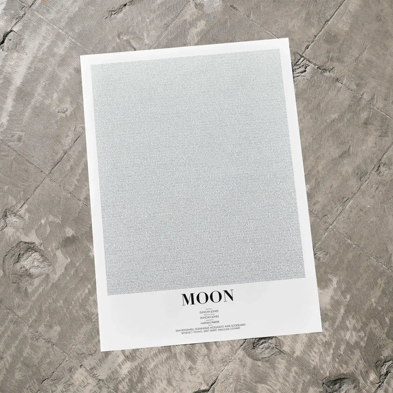 A Moon movie script poster laid flat on a textured floor surface.