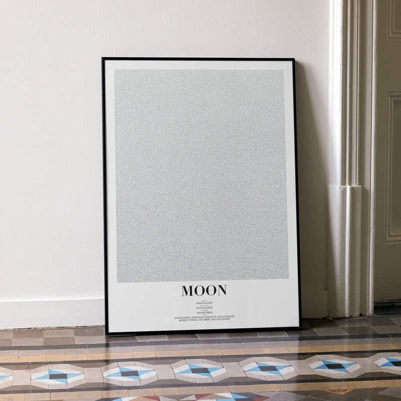 A framed Moon movie script poster leaning against a wall in a minimalist interior.