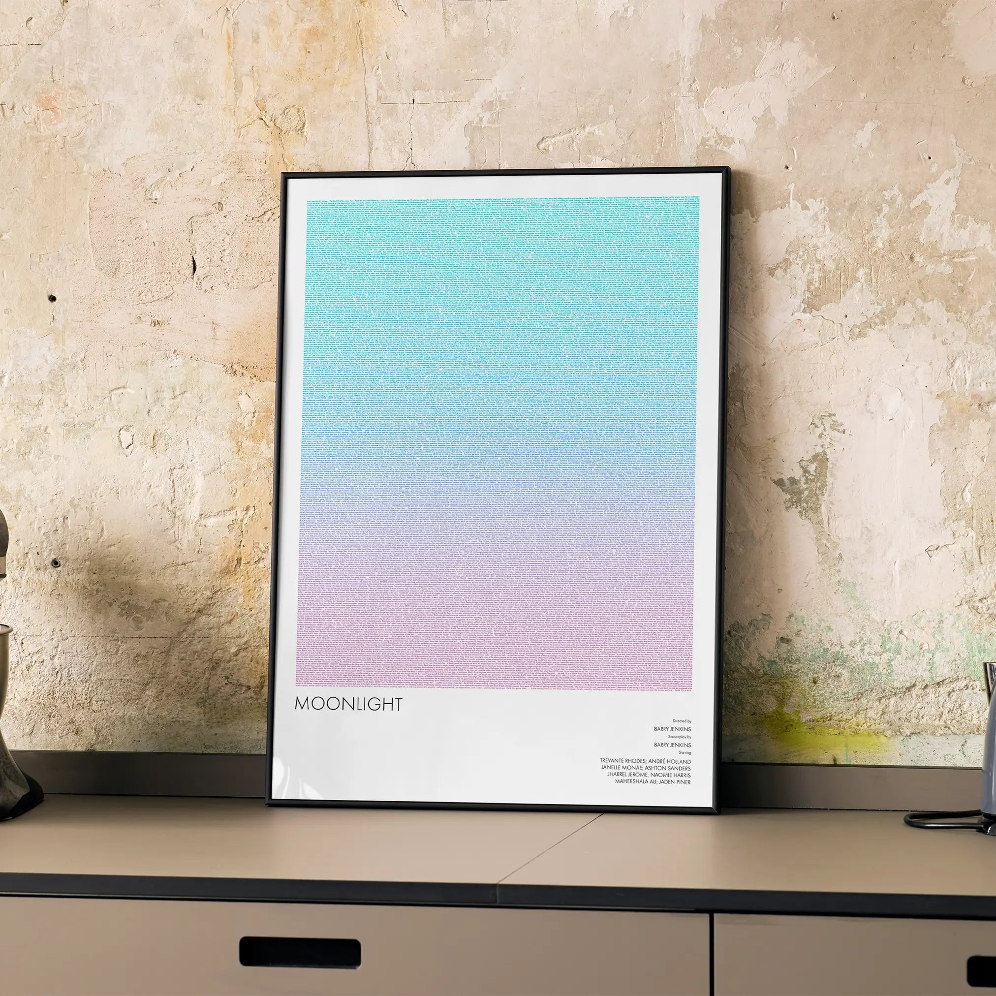 A framed Moonlight movie script poster displayed on a cabinet in a minimalist interior.