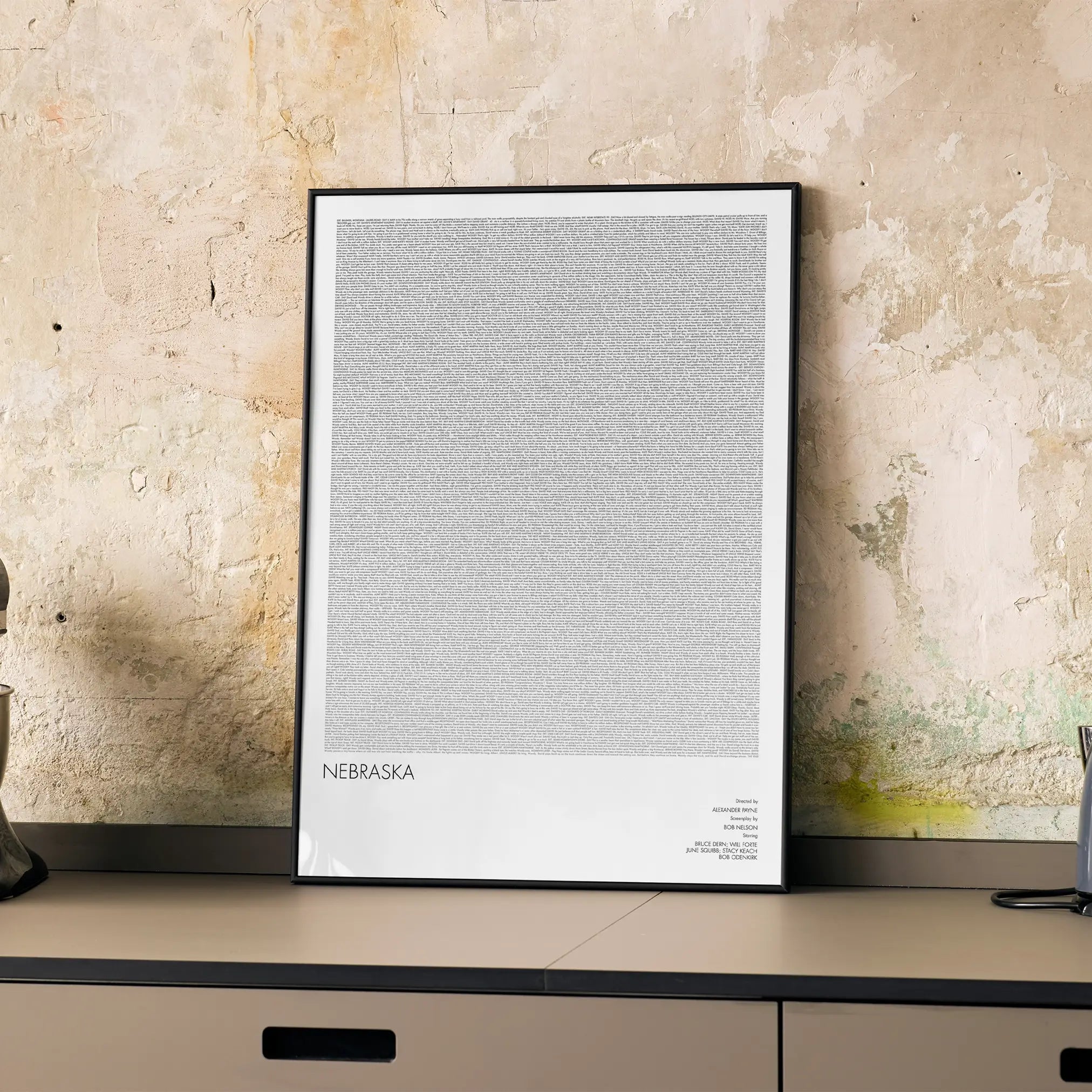 A framed Nebraska movie script poster displayed on a cabinet in a minimalist interior.