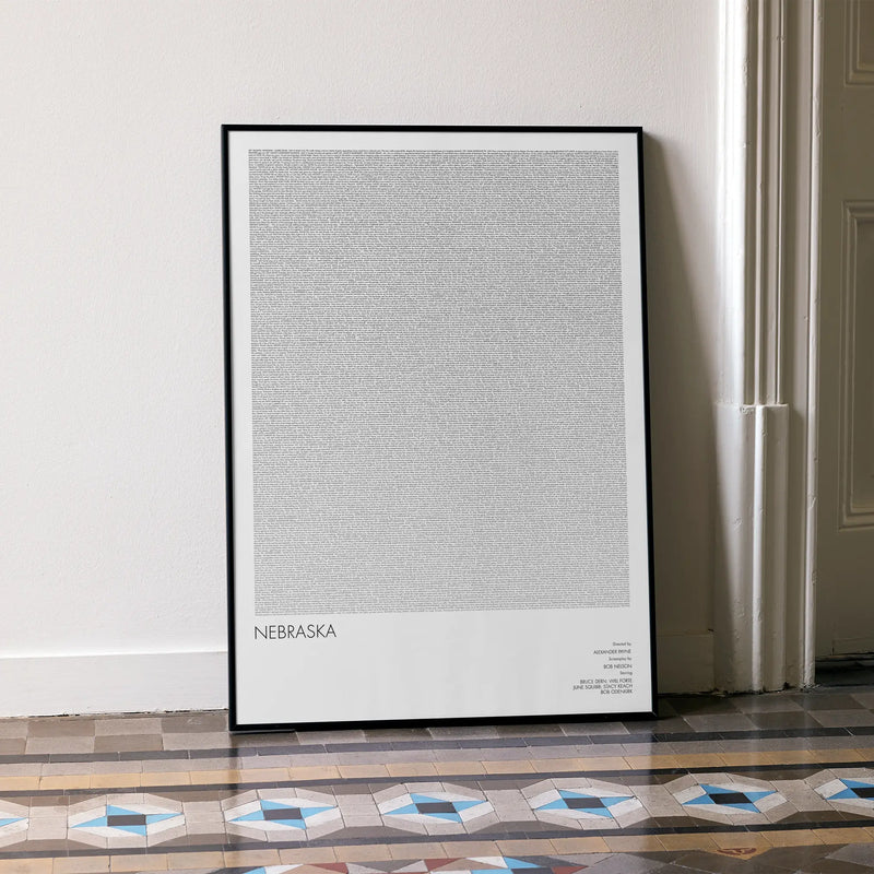A framed Nebraska movie script poster leaning against a wall in a minimalist interior.