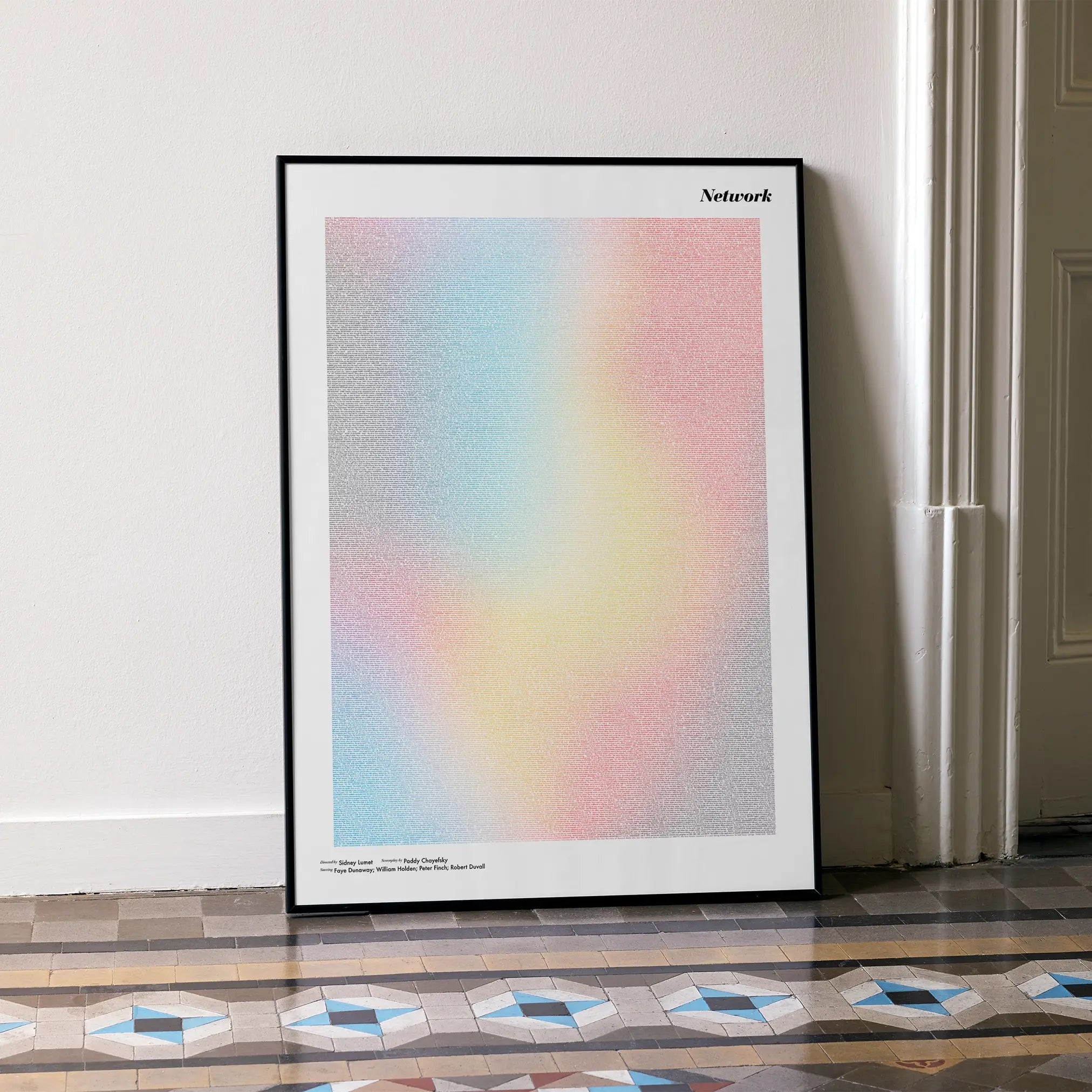 A framed Network movie script poster leaning against a wall in a minimalist interior.