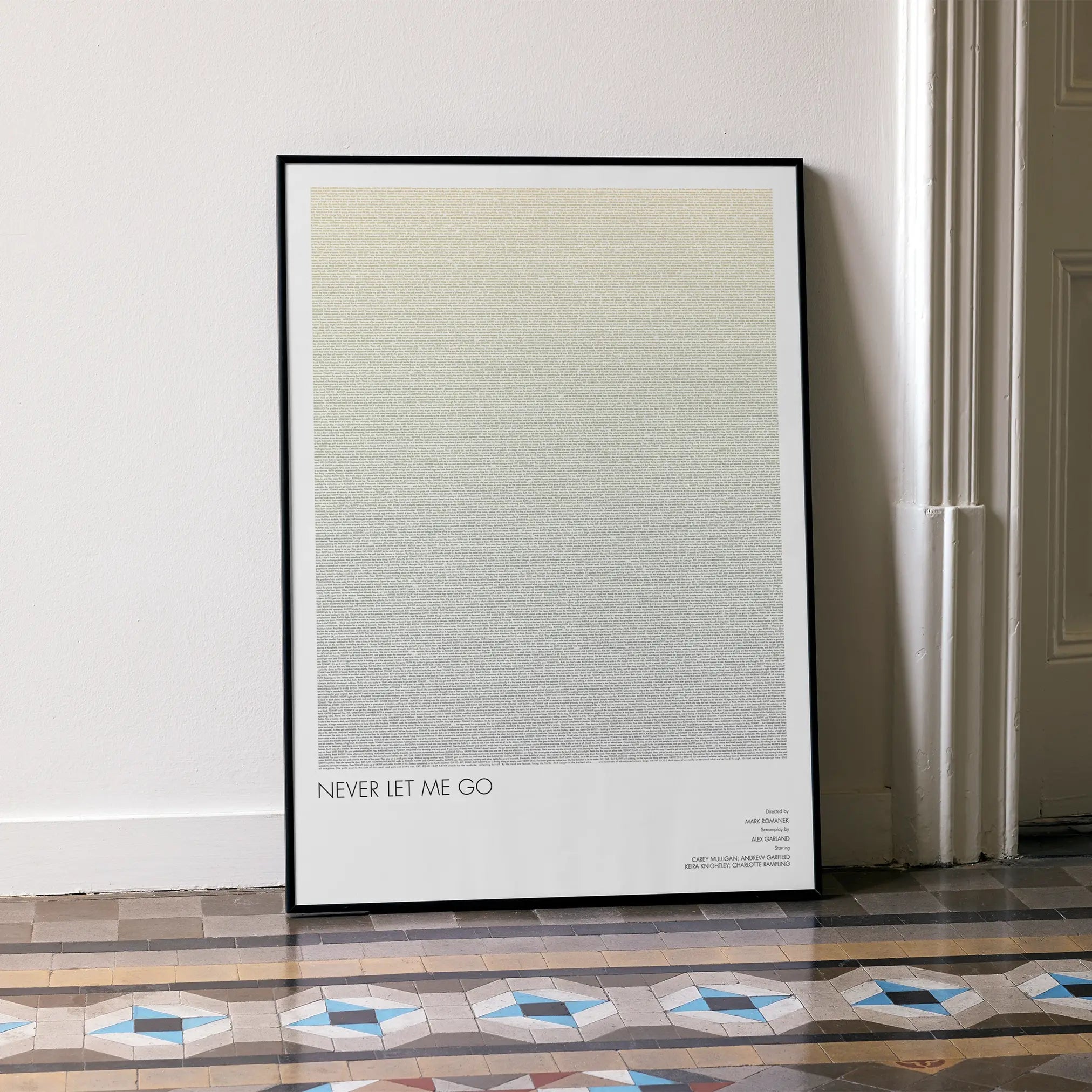 A framed Never Let Me Go movie script poster leaning against a wall in a minimalist interior.