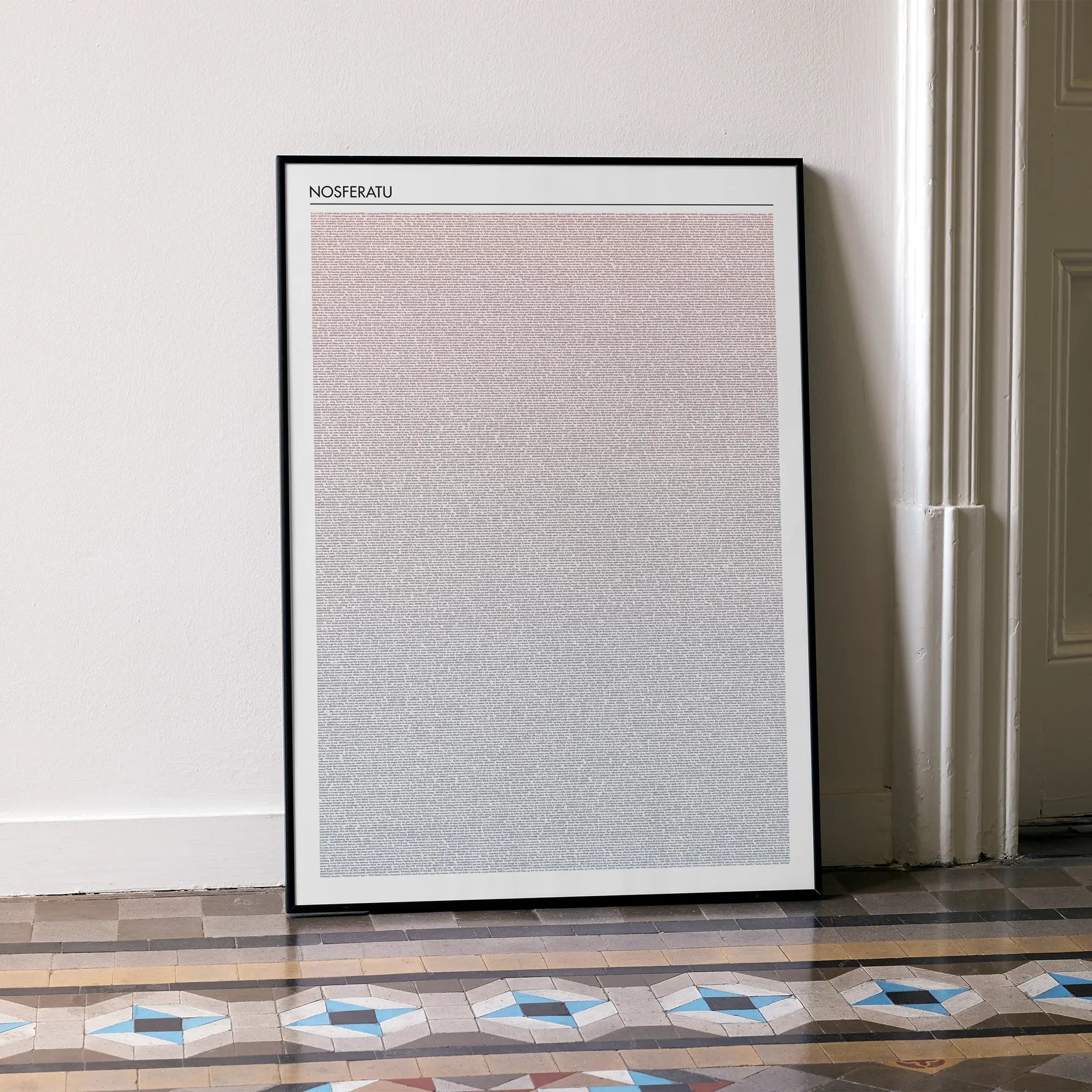 A framed Nosferatu movie script poster leaning against a wall in a minimalist interior.