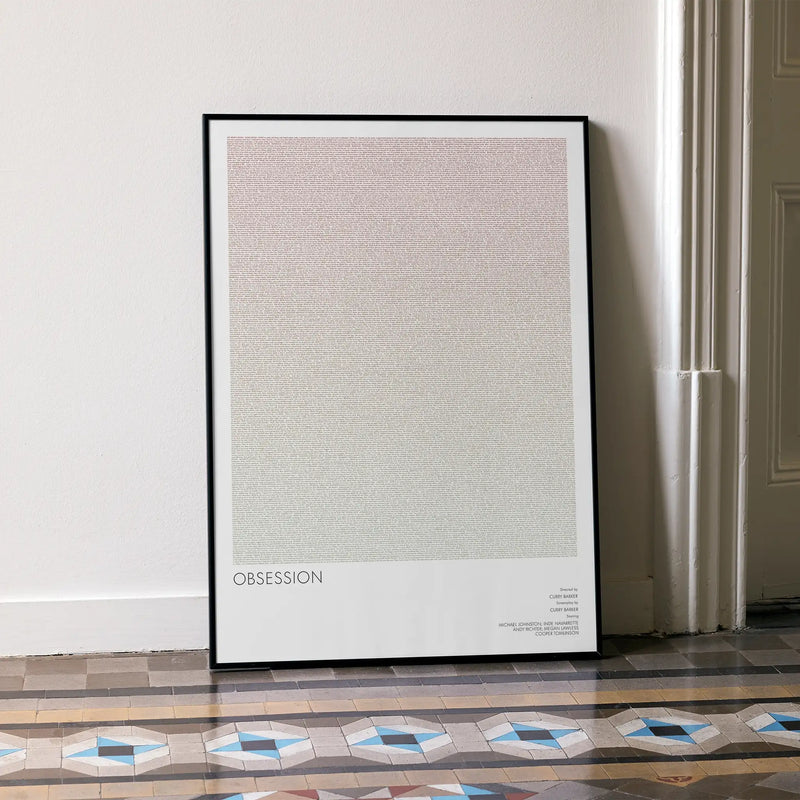 Framed poster titled 'Obsession' on a wall with decorative floor tiles.