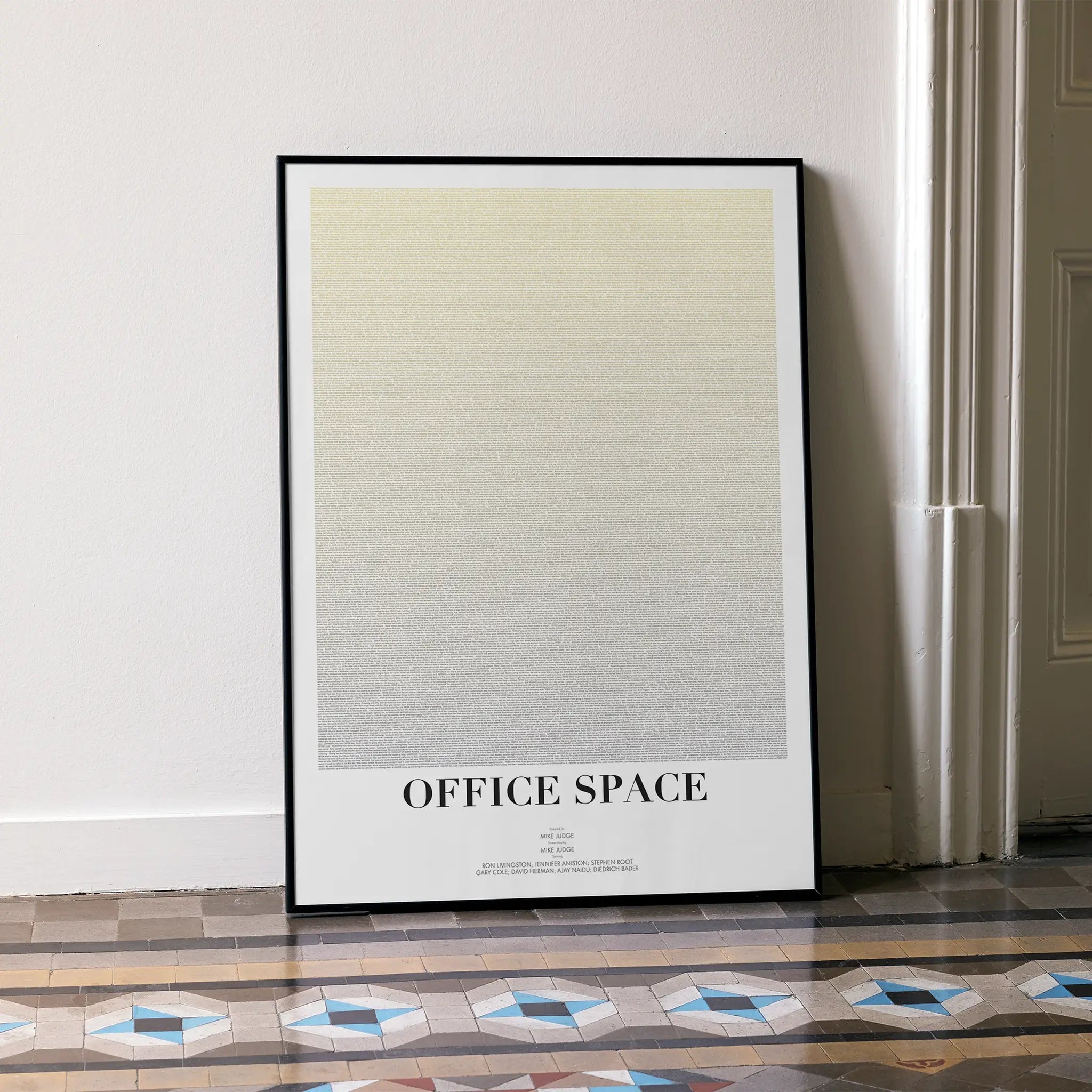 Framed poster for the film'OFFICE SPACE' leaning against a white wall.