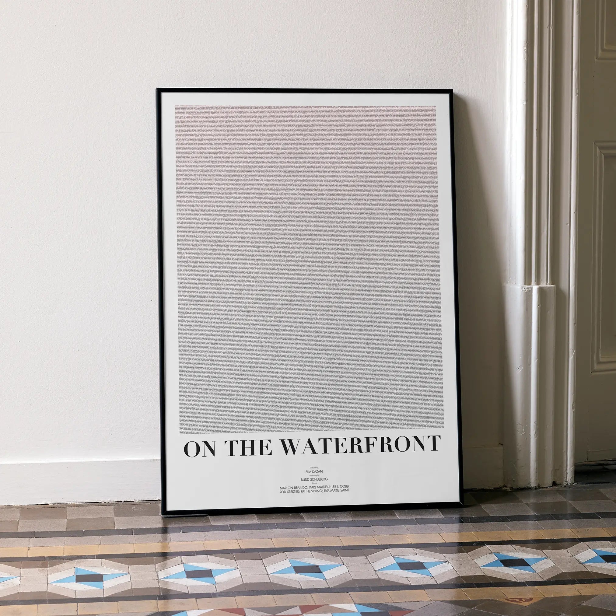 A framed On the Waterfront movie script poster leaning against a wall in a minimalist interior.