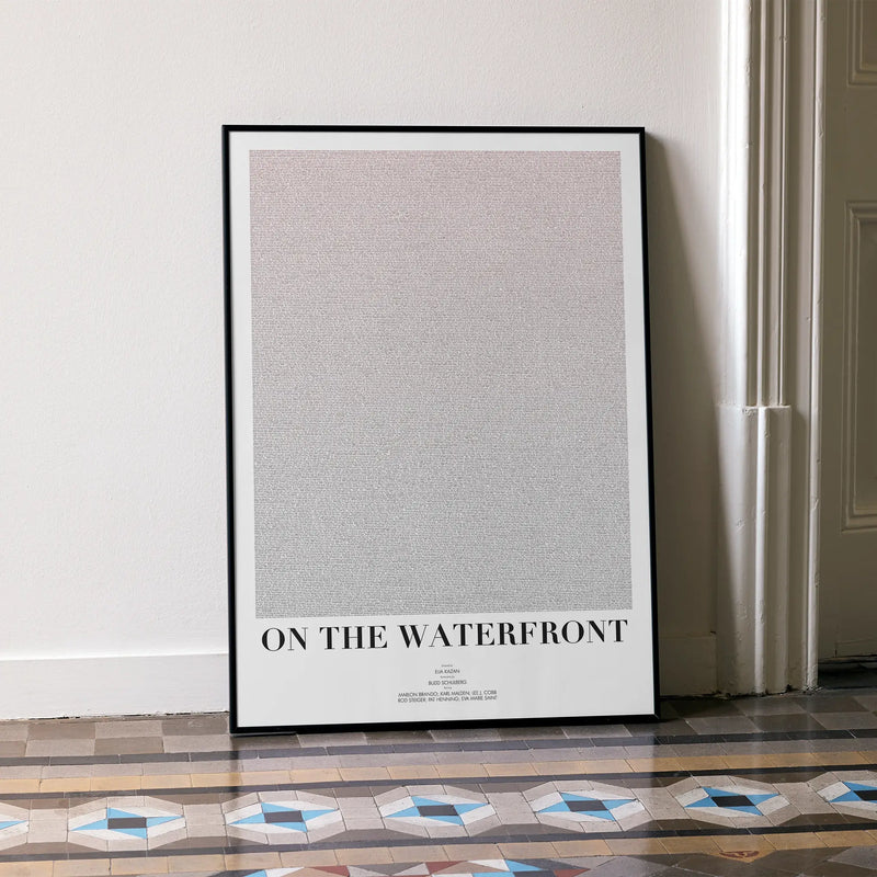 A framed On the Waterfront movie script poster leaning against a wall in a minimalist interior.