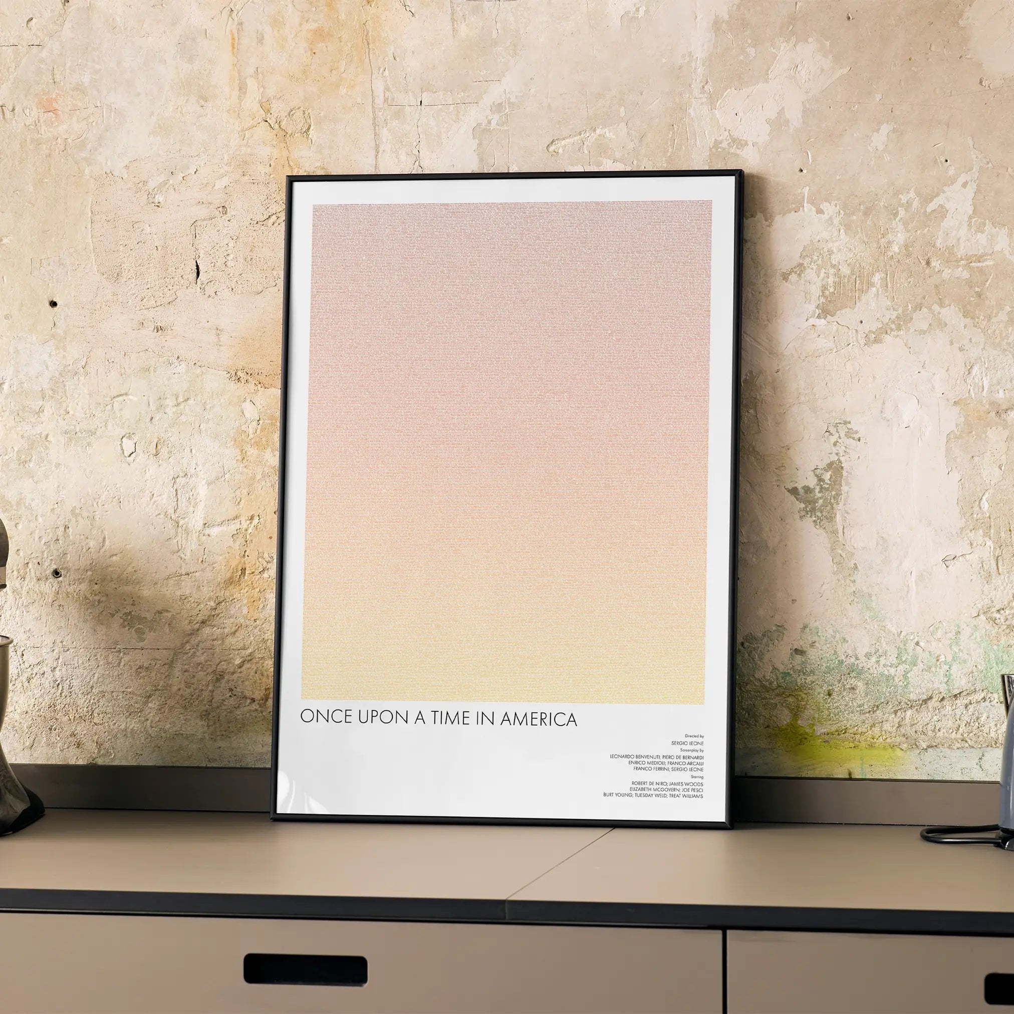 A framed Once Upon a Time in America movie script poster displayed on a cabinet in a minimalist interior.