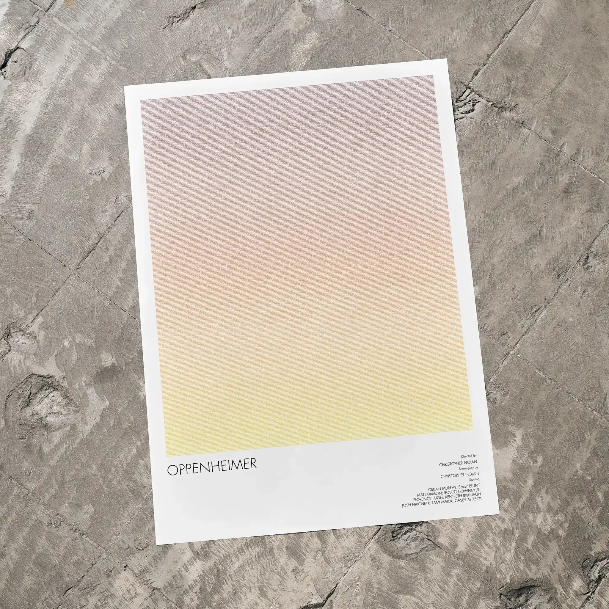 A Oppenheimer movie script poster laid flat on a textured floor surface.