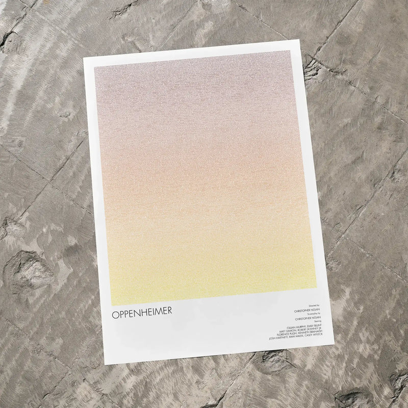 A Oppenheimer movie script poster laid flat on a textured floor surface.