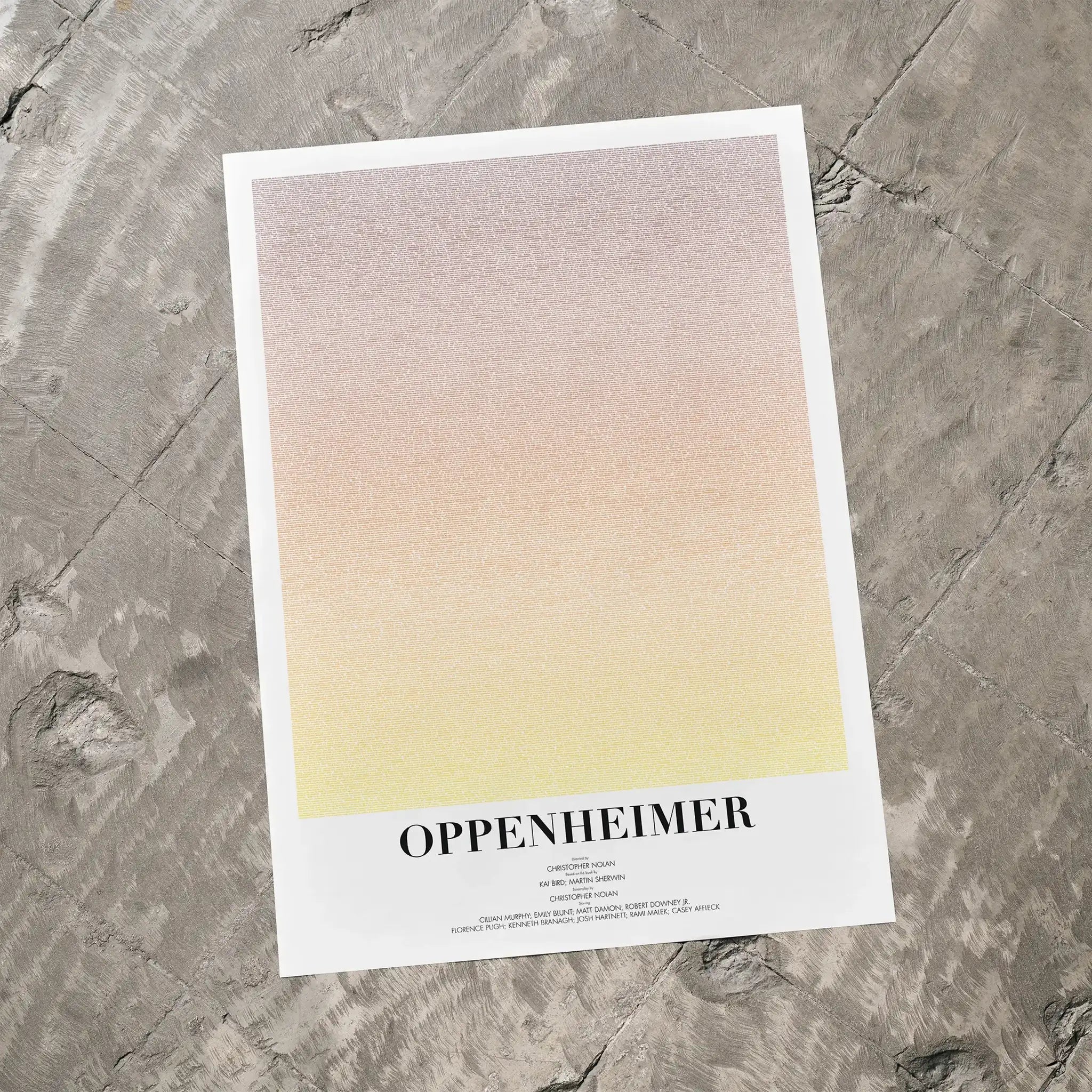A Oppenheimer movie script poster laid flat on a textured floor surface.