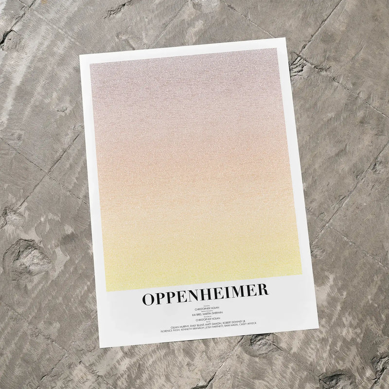 A Oppenheimer movie script poster laid flat on a textured floor surface.