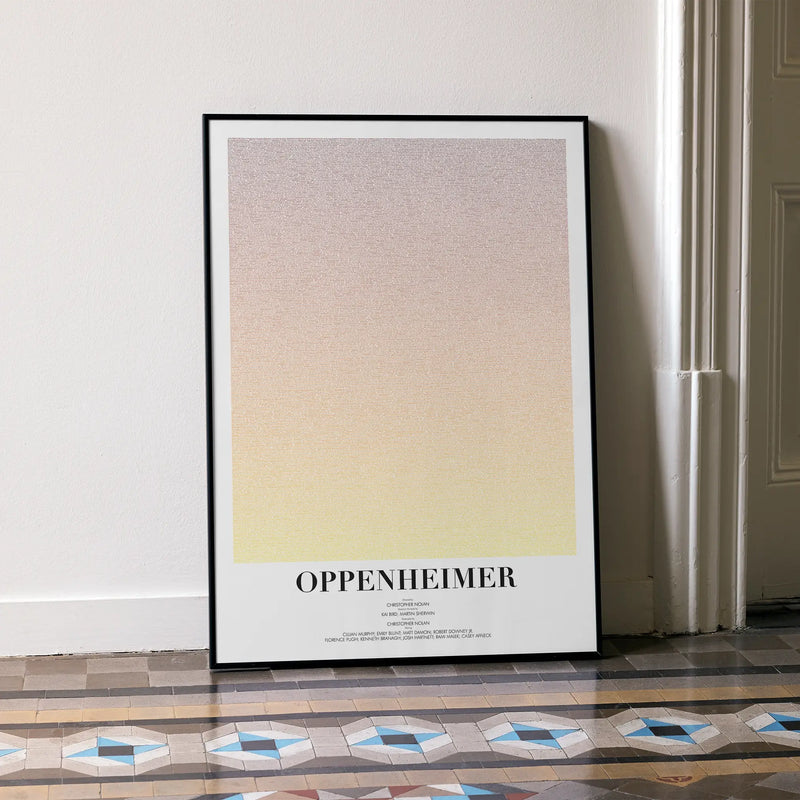 A framed Oppenheimer movie script poster leaning against a wall in a minimalist interior.