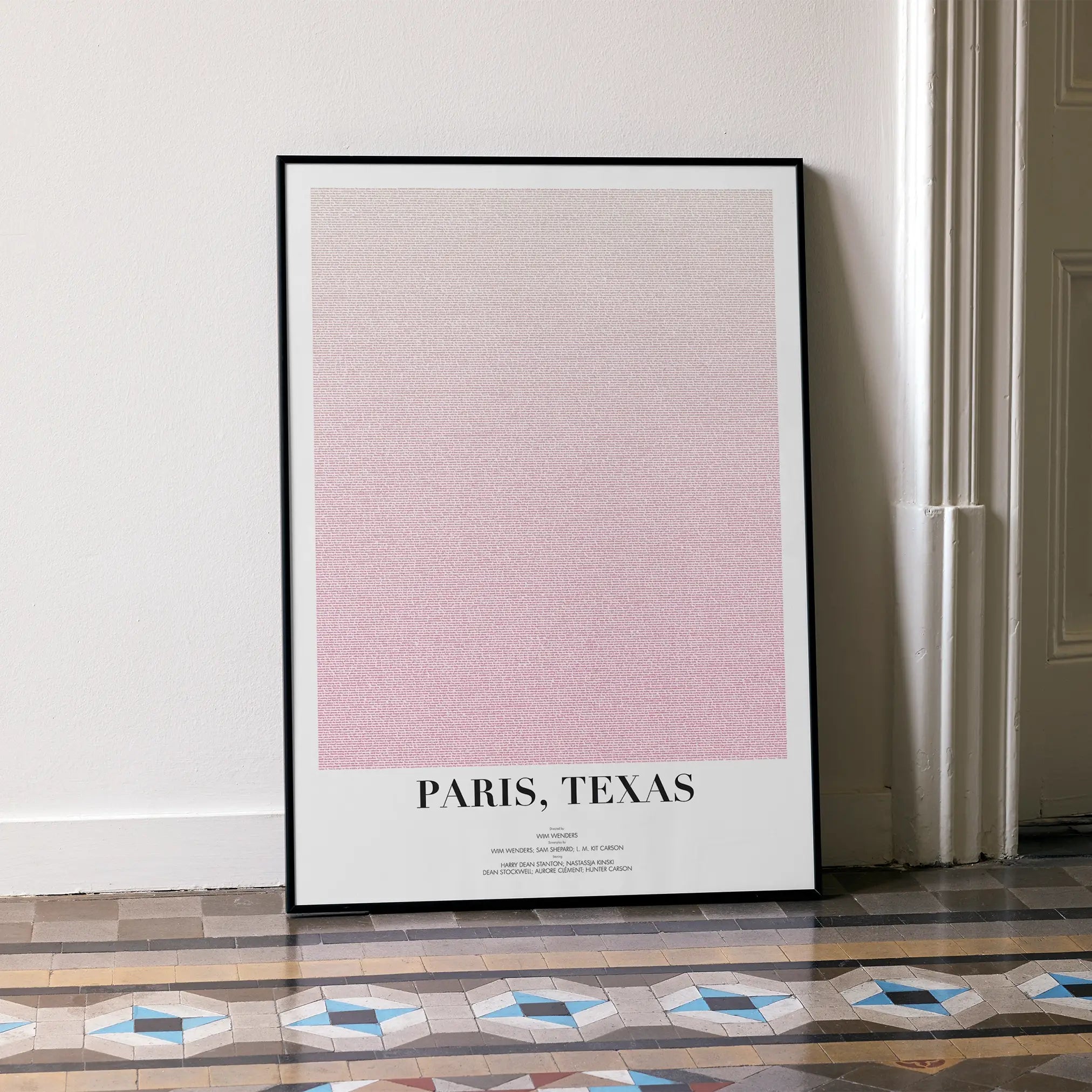 A framed Paris, Texas movie script poster leaning against a wall in a minimalist interior.