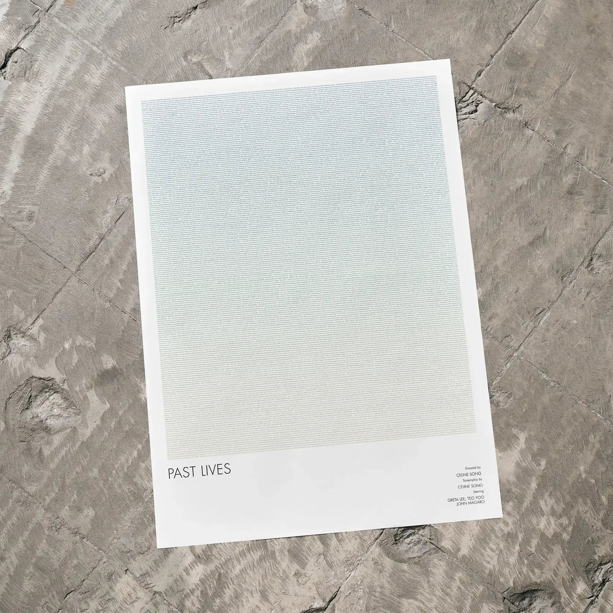 A Past Lives movie script poster laid flat on a textured floor surface.