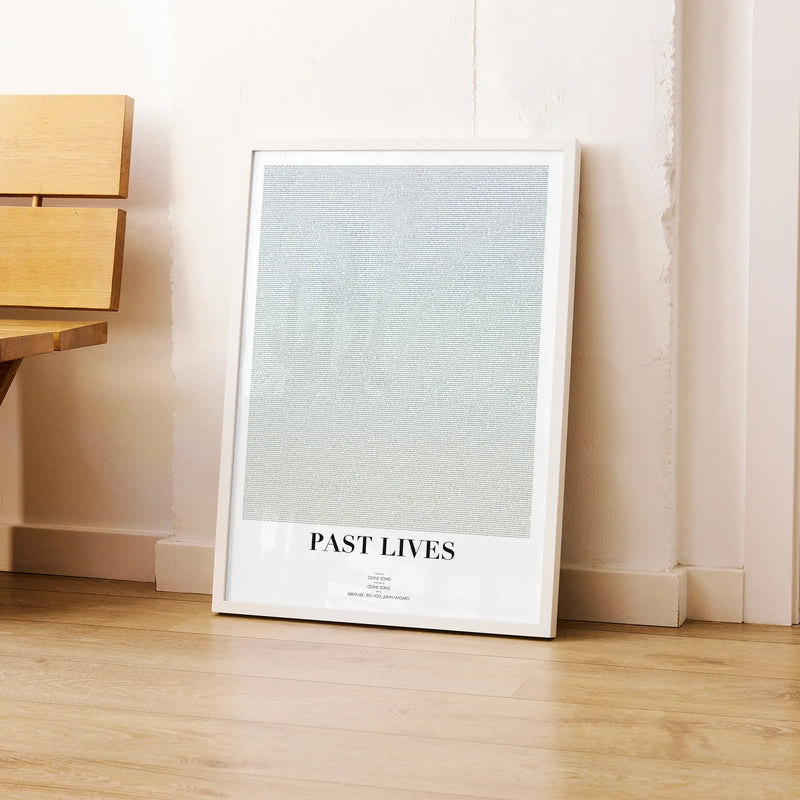 A framed Past Lives movie script poster leaning against a wall in a modern interior.