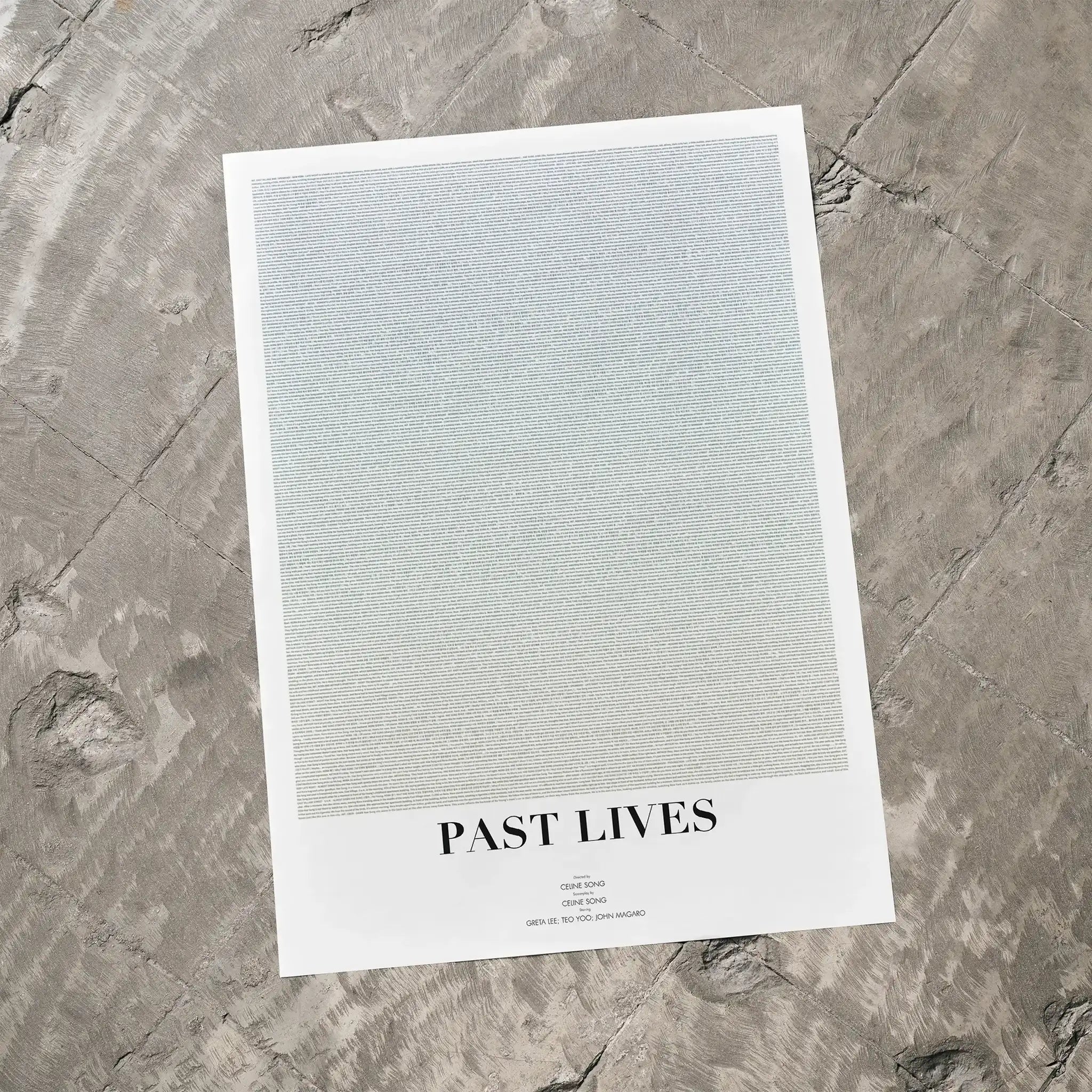A Past Lives movie script poster laid flat on a textured floor surface.