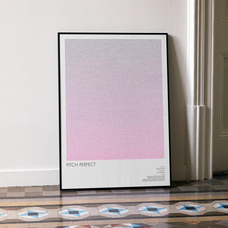A framed Pitch Perfect movie script poster leaning against a wall in a minimalist interior.