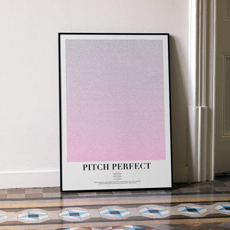 A framed Pitch Perfect movie script poster leaning against a wall in a minimalist interior.