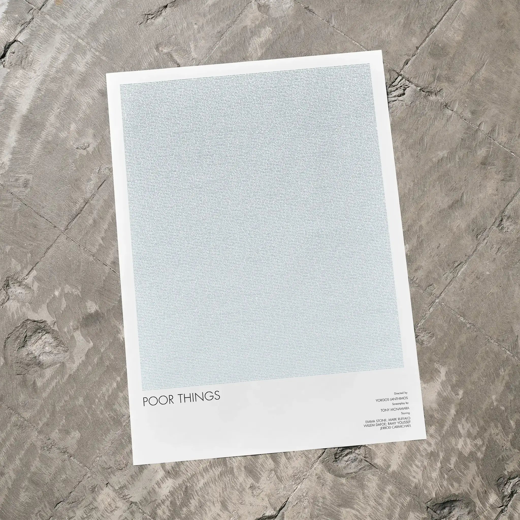 A Poor Things movie script poster laid flat on a textured floor surface.