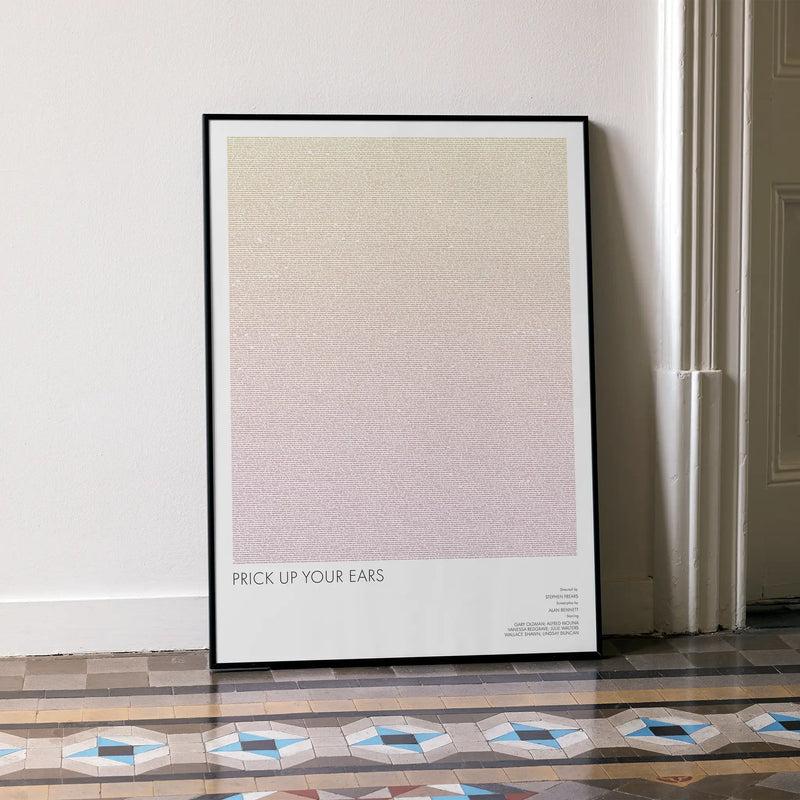 A framed Prick Up Your Ears movie script poster leaning against a wall in a minimalist interior.