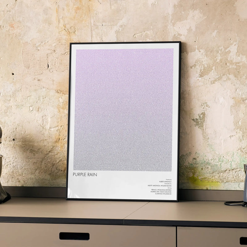 A framed Purple Rain movie script poster displayed on a cabinet in a minimalist interior.