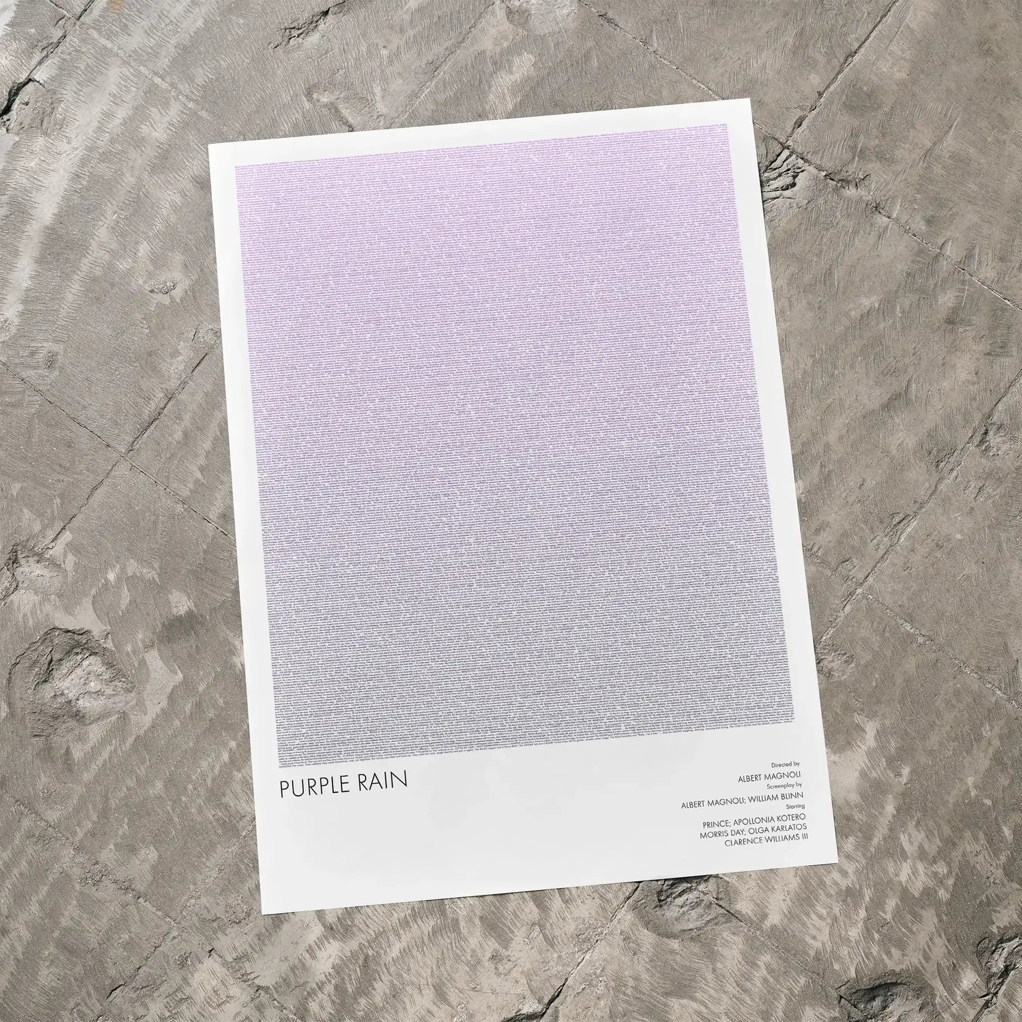 A Purple Rain movie script poster laid flat on a textured floor surface.