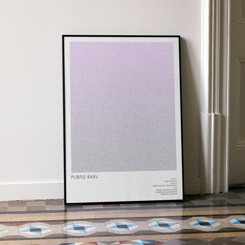 A framed Purple Rain movie script poster leaning against a wall in a minimalist interior.