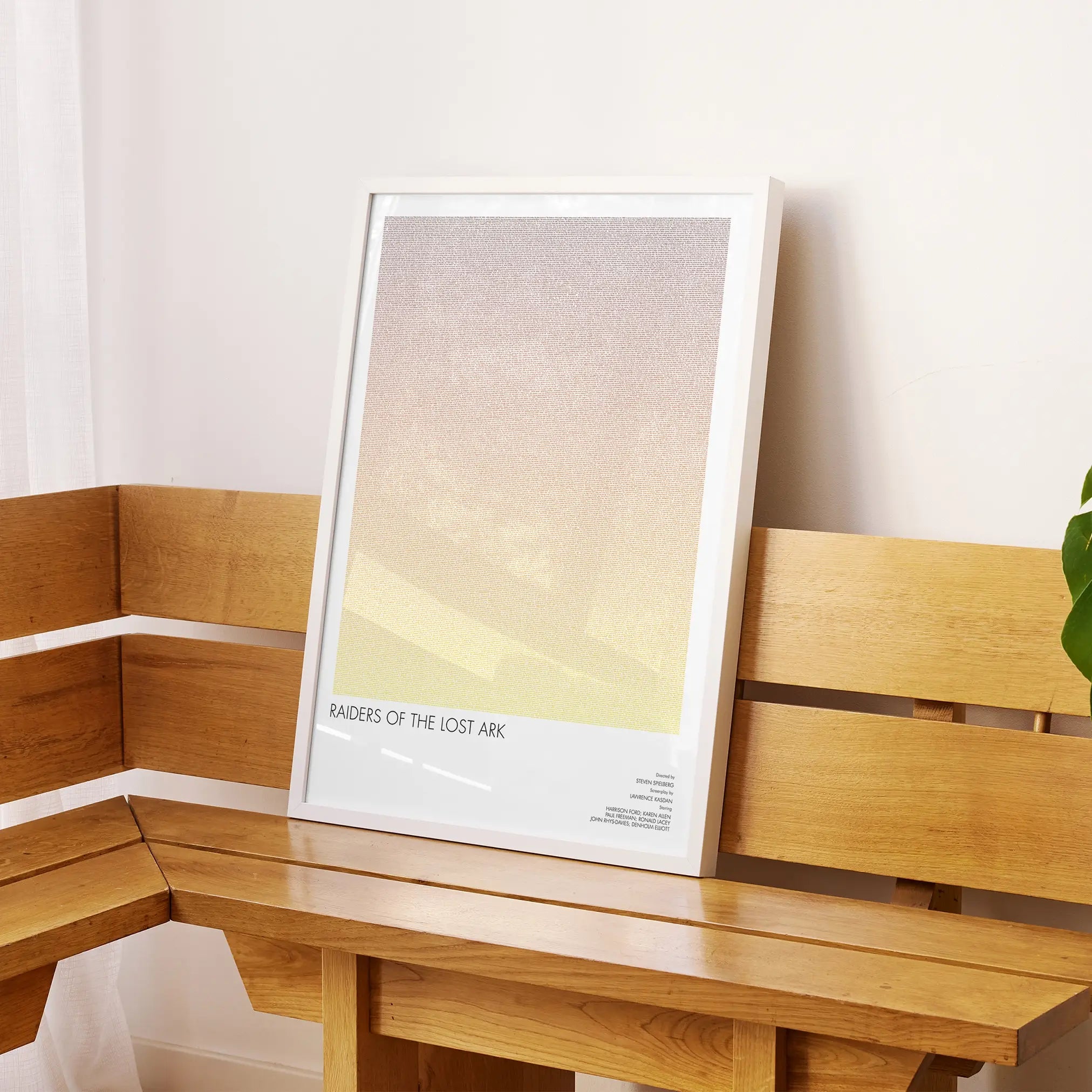 A framed Raiders of the Lost Ark movie script poster displayed on a sideboard in a contemporary space.
