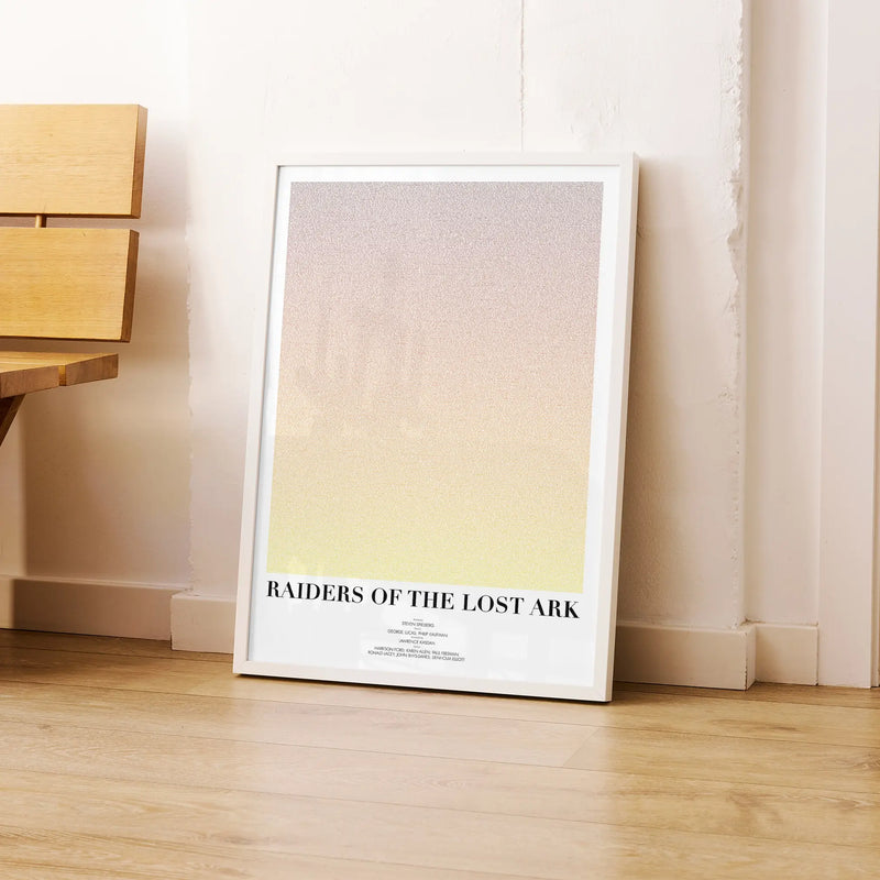 A framed Raiders of the Lost Ark movie script poster leaning against a wall in a modern interior.