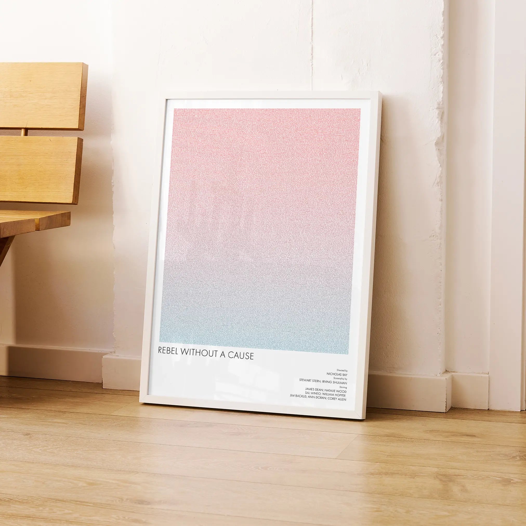 A framed Rebel Without a Cause movie script poster leaning against a wall in a modern interior.