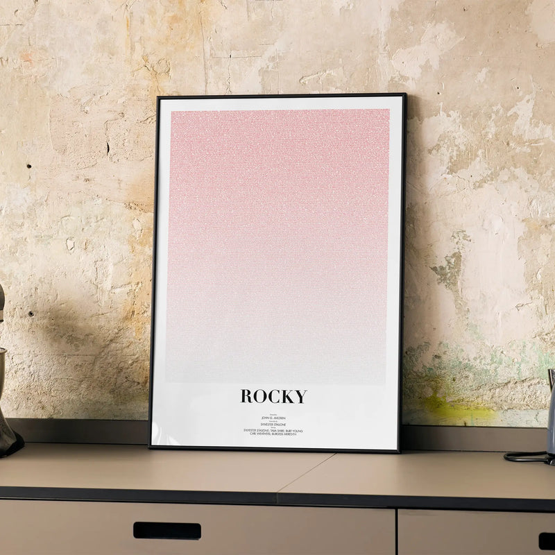 A framed Rocky movie script poster displayed on a cabinet in a minimalist interior.