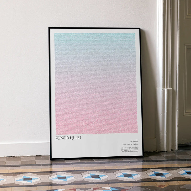 A framed Romeo + Juliet movie script poster leaning against a wall in a minimalist interior.