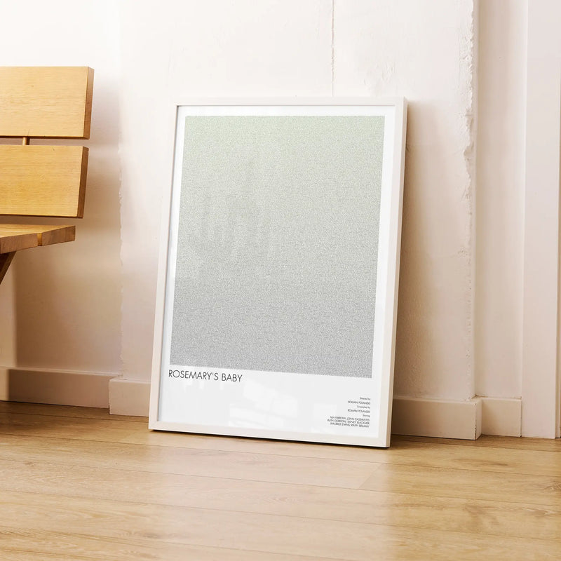 A framed Rosemary's Baby movie script poster leaning against a wall in a modern interior.