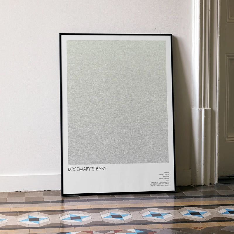 A framed Rosemary's Baby movie script poster leaning against a wall in a minimalist interior.