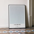 A framed Saltburn movie script poster leaning against a wall in a minimalist interior.