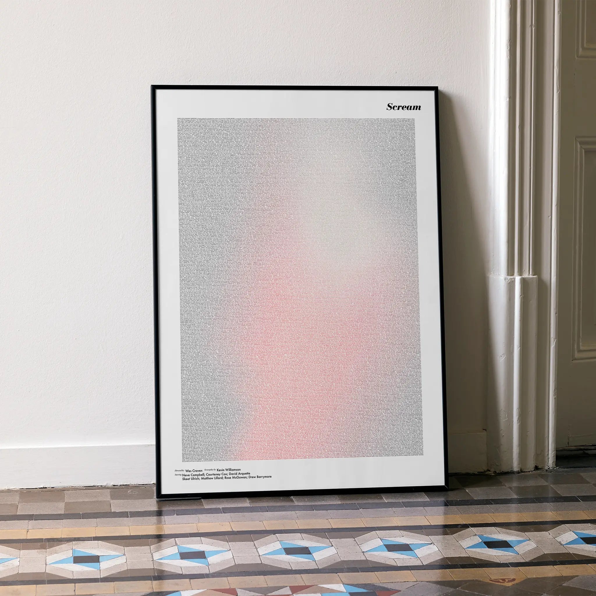 A framed Scream movie script poster leaning against a wall in a minimalist interior.