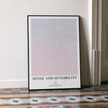 A framed Sense and Sensibility movie script poster leaning against a wall in a minimalist interior.